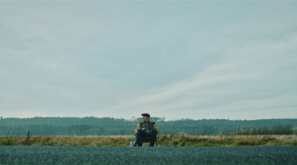 man sitting on chair next to empty road