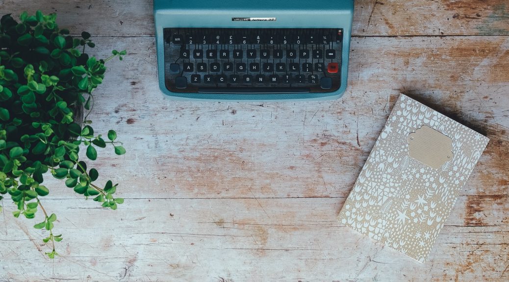 typewriter with plant and notebook