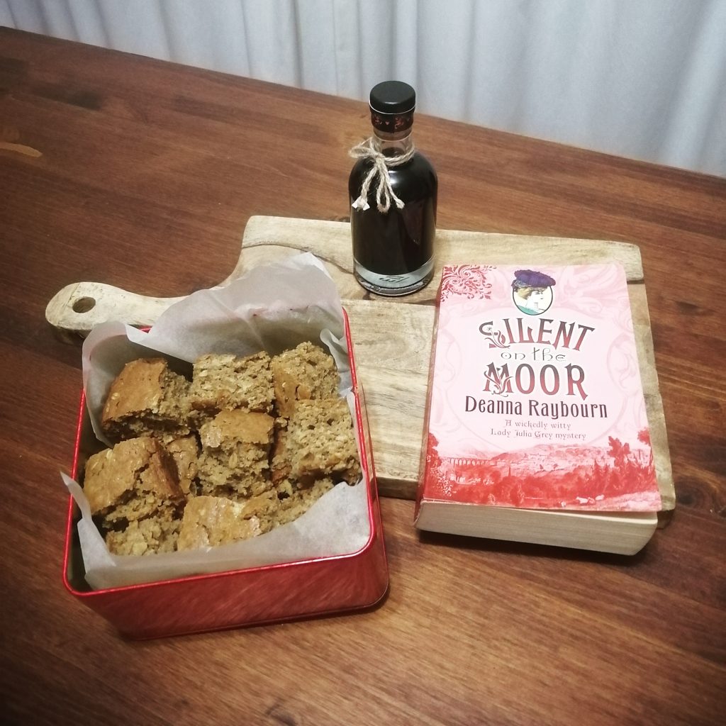 pink book, parkins in red tin, and botte of coffee liquor on wooden board on table